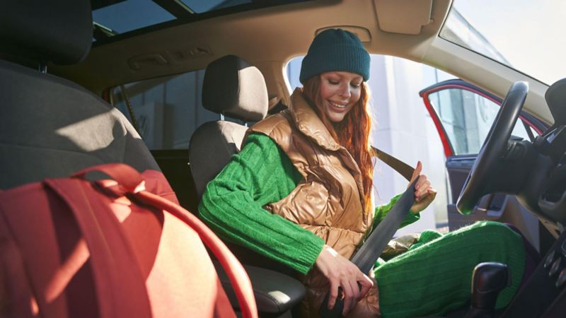 Une femme s'installe dans sa voiture Volkswagen et attache sa ceinture de sécurité.