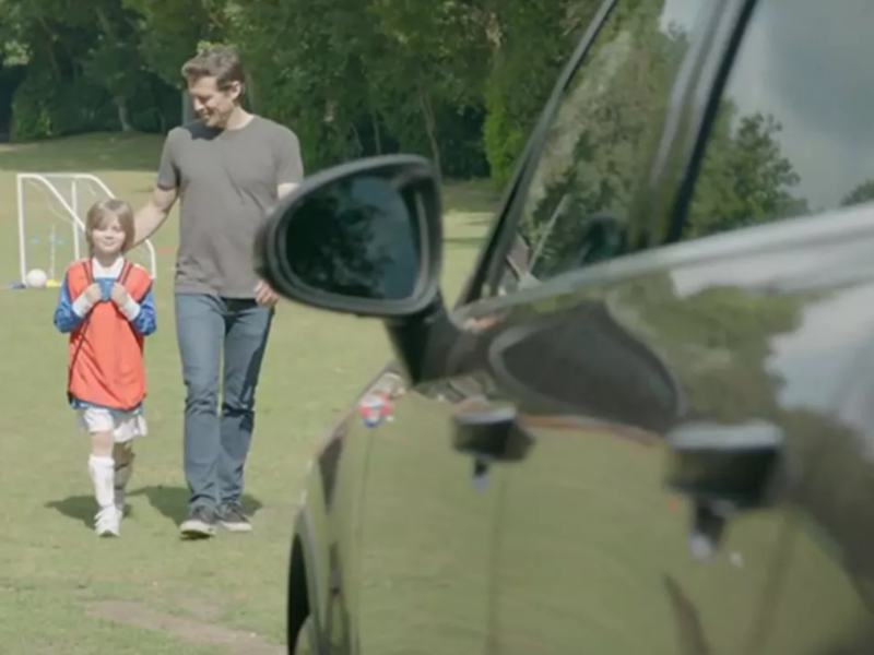 Man and boy walking towards a car on a football pitch