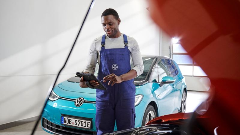 Technician reviewing his checklist in front of an electric car