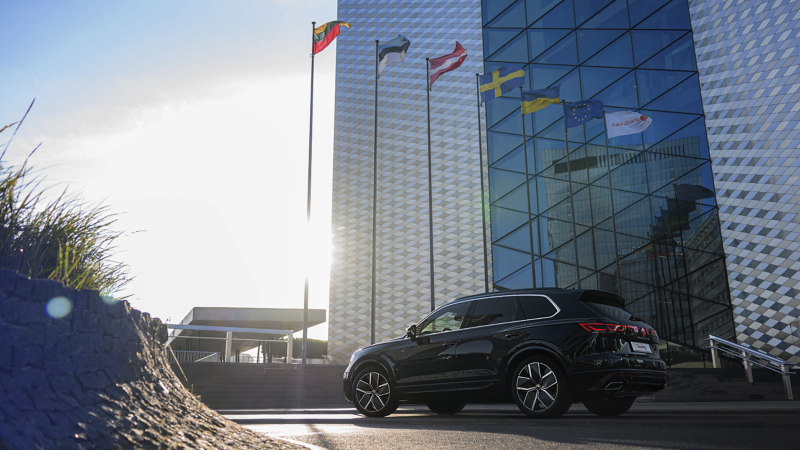 A VW Touareg R-Line drives across a road, view from the side.