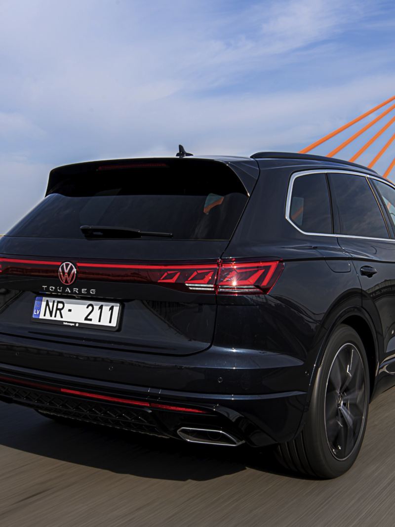 A VW Touareg R-Line drives across a road, view from the side.