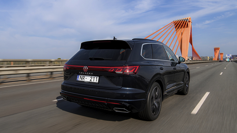 A VW Touareg R-Line drives across a road, view from the side.