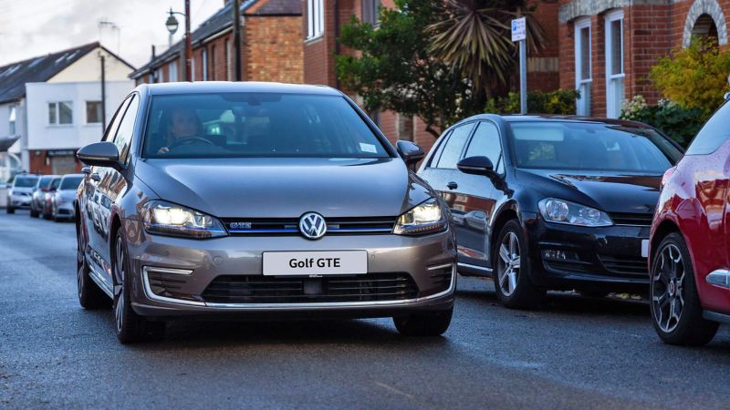 Angel driving her Golf GTE along a road in a built up street