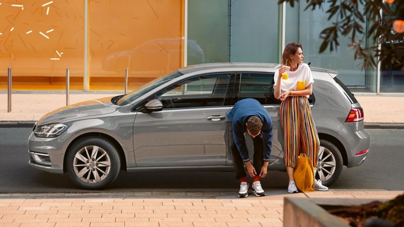 Man and woman leaning against a VW Golf