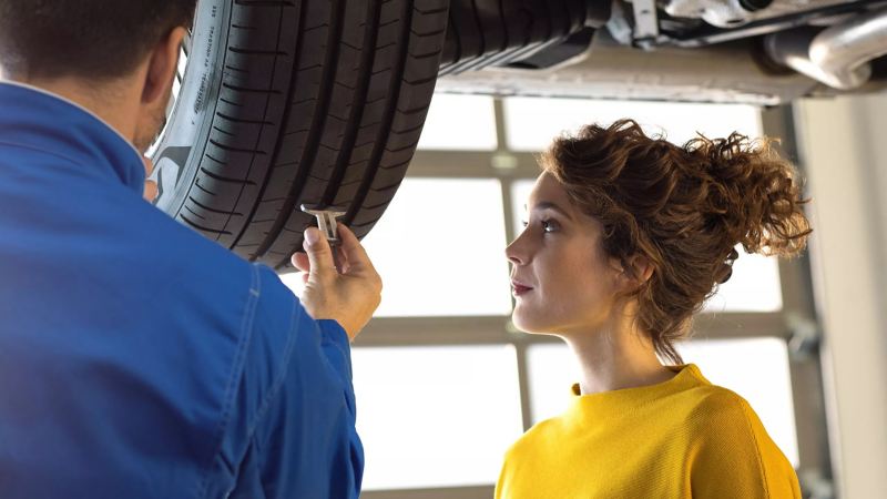 Un propriétaire regardant un expert travaillant sur sa voiture Volkswagen