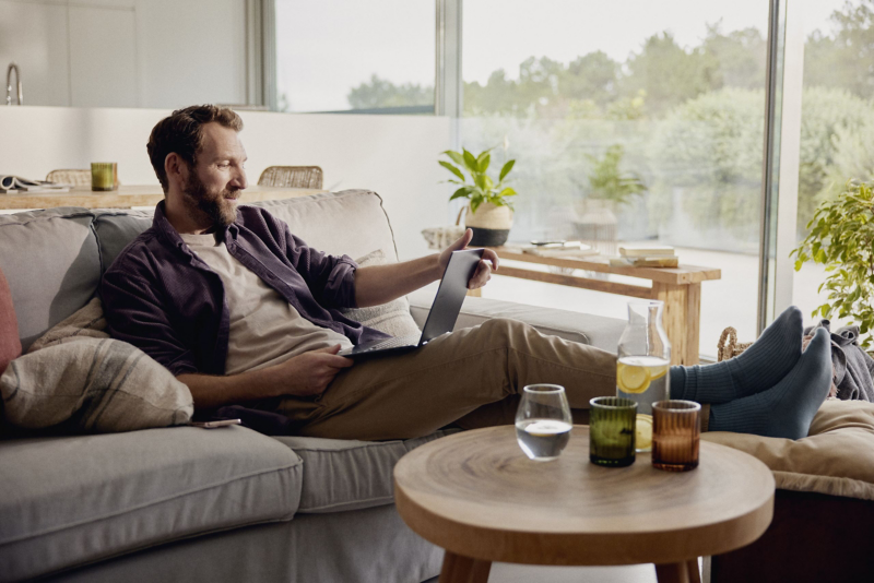 Man sat on the sofa with feet up and laptop on his lap