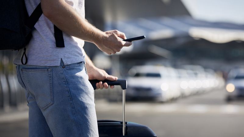 Ein Mann schaut an einem Flughafenterminal auf sein Handy. 