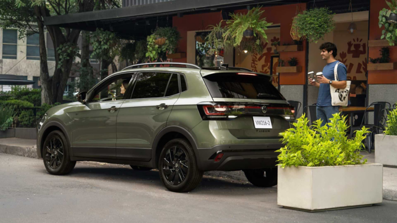 Volkswagen Taigun verde frente a una cafetería, con un hombre junto al vehículo.Modificado con inteligencia artificial