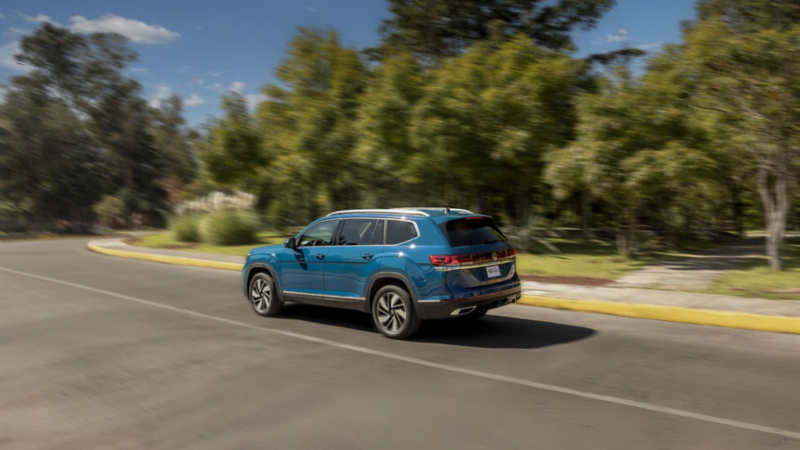Camioneta Teramont. Vista trasera de SUV de color azul en movimiento sobre carretera rodeada de árboles.