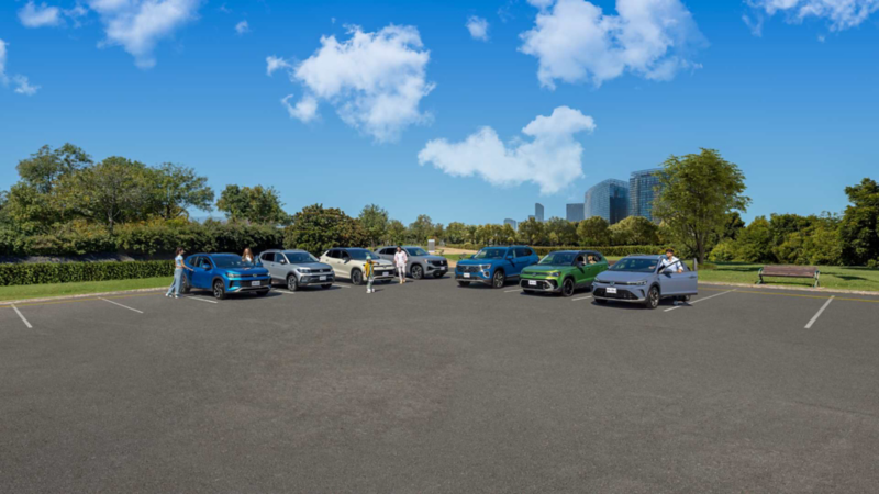 Familia de camionetas SUV Volkswagen 2026 en exhibición en un estacionamiento con parque de fondo.