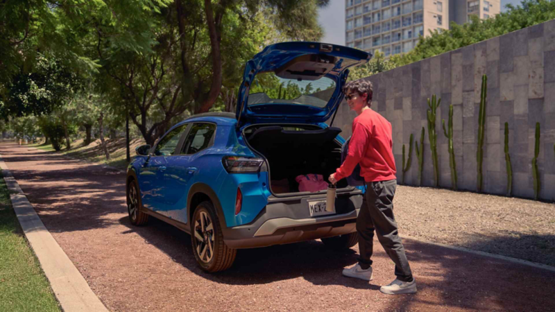 Hombre guarda termo en cajuela abierta de VW Tera de color azul en parque.