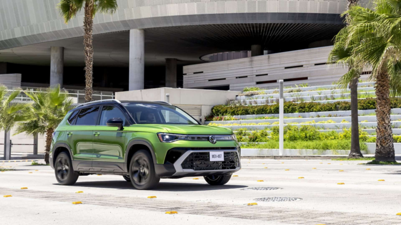 Nuevo Taos de Volkswagen a las afueras de un edificio moderno con jardineras. 