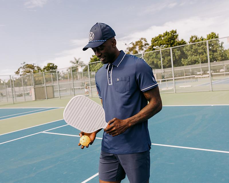 A man on a pickelball court wearing a DriverGear polo and hat.