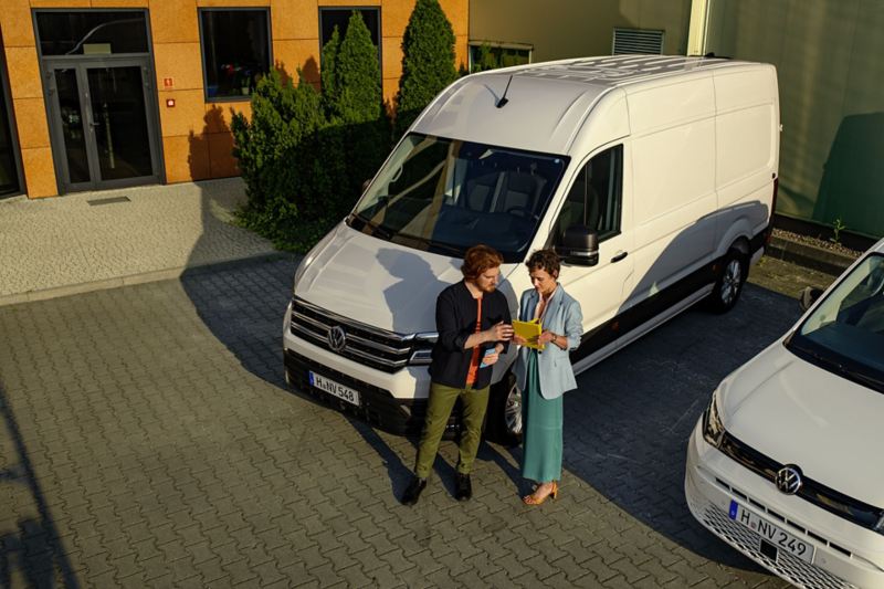 un homme et une femme devant un Crafter VW blanc et un Caddy VW blanc