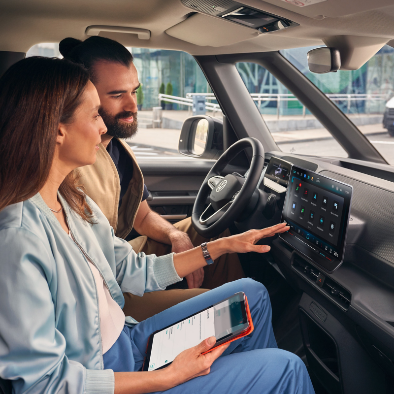 Man och kvinna sitter i en VW ID. Buzz Cargo och tittar på infotainmentskärmen