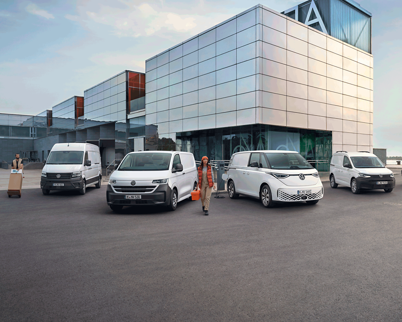 Le VW Transporter, le VW Caddy, l'ID. Buzz Cargo et le VW Crafter devant un immeuble moderne.