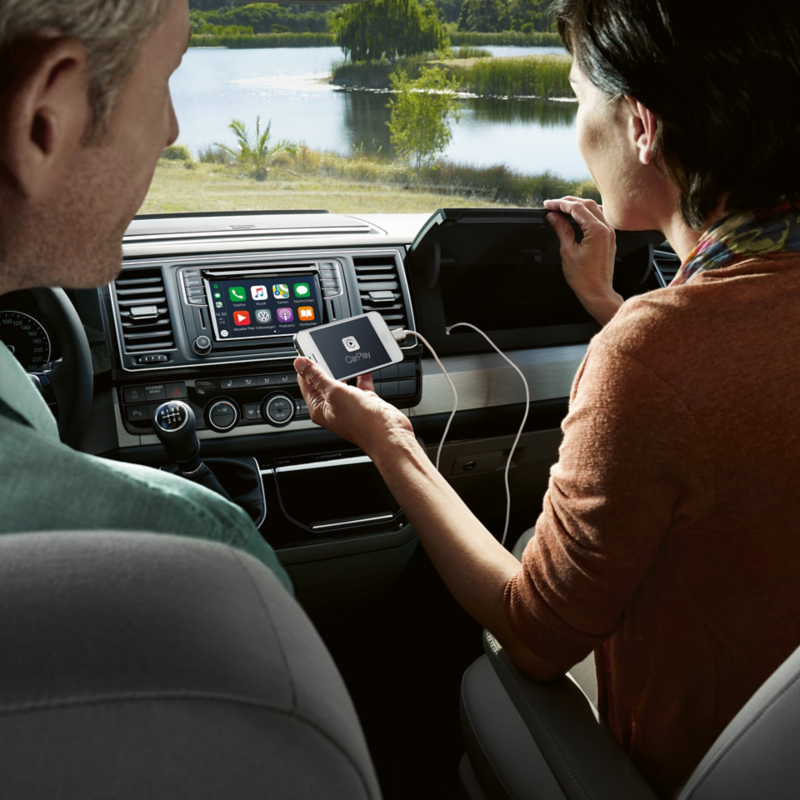 A woman connects a smartphone to a USB port in the glove compartment.