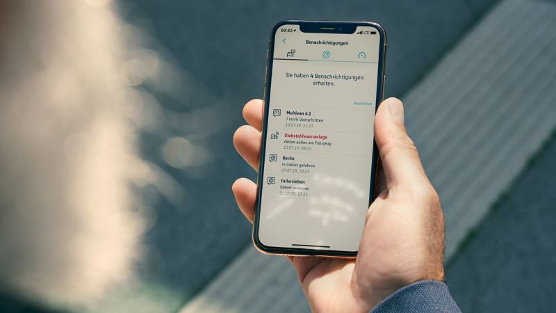 Een man kijkt op zijn smartphone met de dienst Online Anti-Diefstal Alarm geopend in de We Connect-app.