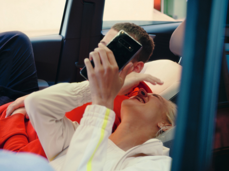 A young woman and a young man sitting in a Volkswagen ID.3 with the seats reclined and laughing