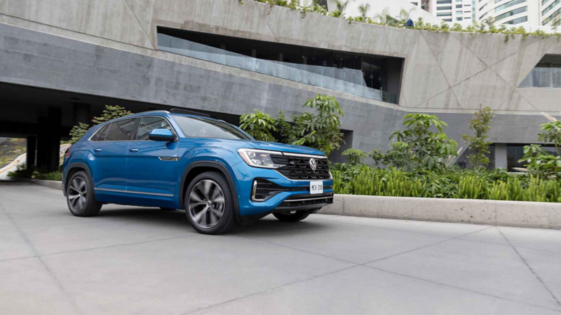 SUV de Volkswagen en color azul circula cerca de edificio moderno.