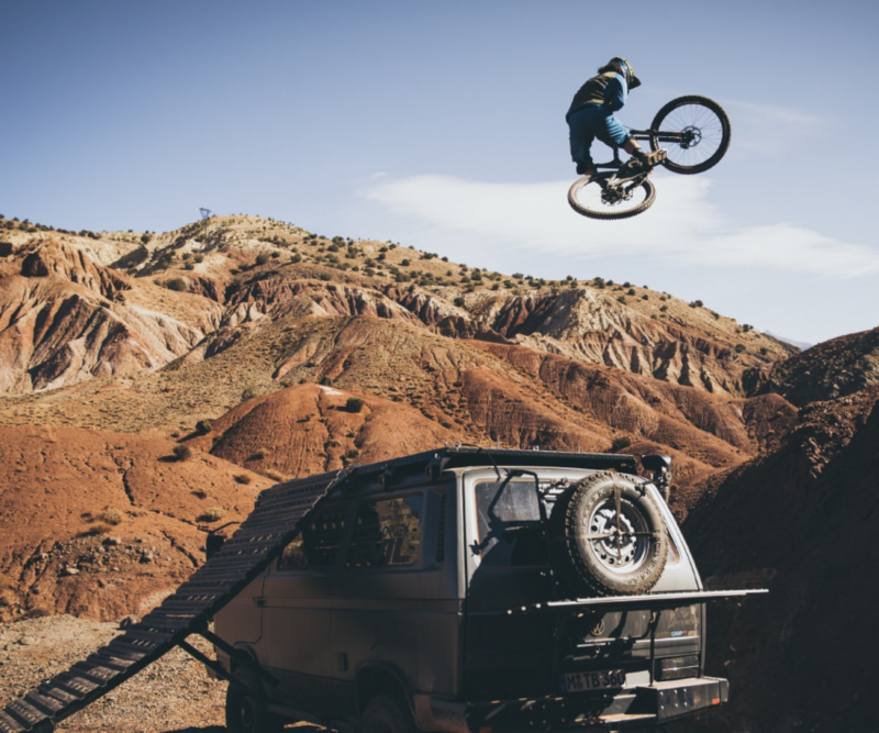 Rob Heran macht einen spektakulären Sprung mit dem Mountainbike – über seinen T3 Bus hinweg.