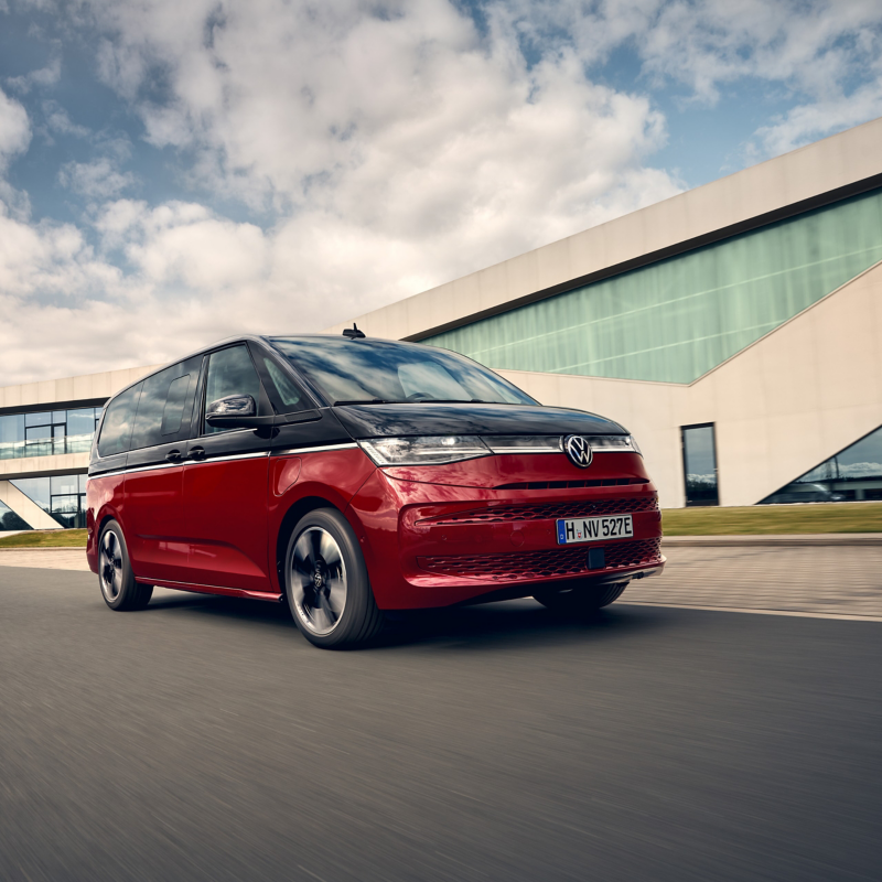 En röd-svart VW Multivan i stan.
