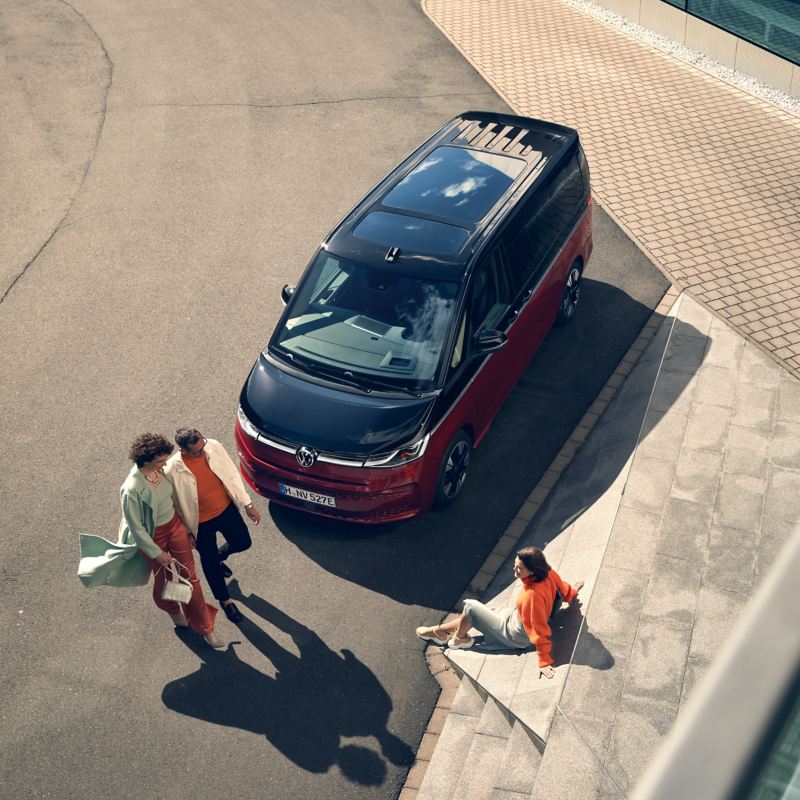 Un groupe de personnes devant un VW Multivan Style en vue oblique de dessus.