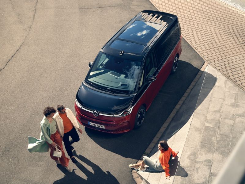 Eine Gruppe Menschen vor einem VW Multivan Style schräg von oben.