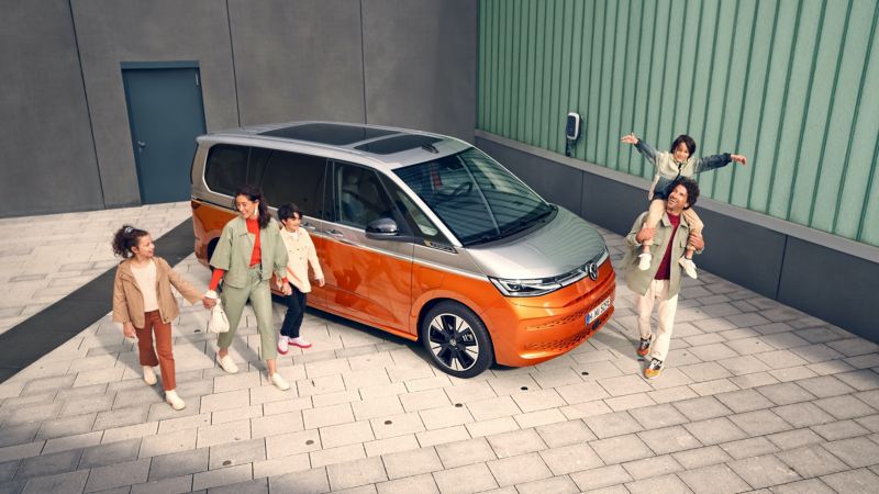 Une famille marche joyeusement à côté du VW Multivan Energetic à l’arrêt.