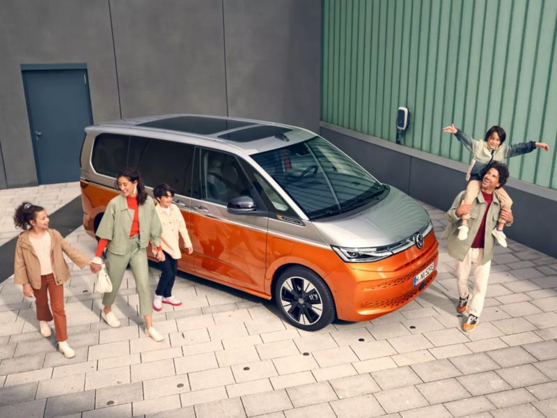 Une famille marche joyeusement à côté du VW Multivan Energetic à l’arrêt.