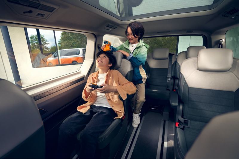 Två barn leker i nya VW Multivan laddhybrids rymlig interiör