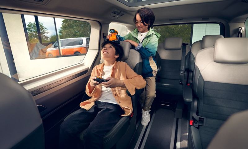 Zwei Kinder spielen im Innenraum des VW Multivan.