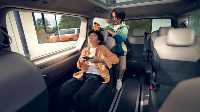 兩個小孩在New Multivan上透過玻璃車頂看空拍機