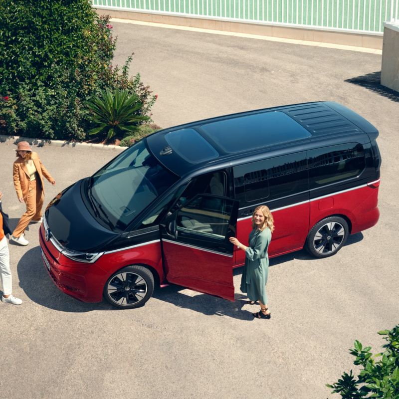 A family happily walks alongside the stationary VW Multivan Energetic.