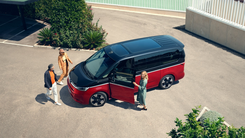 A family happily walks alongside the stationary VW Multivan Energetic.