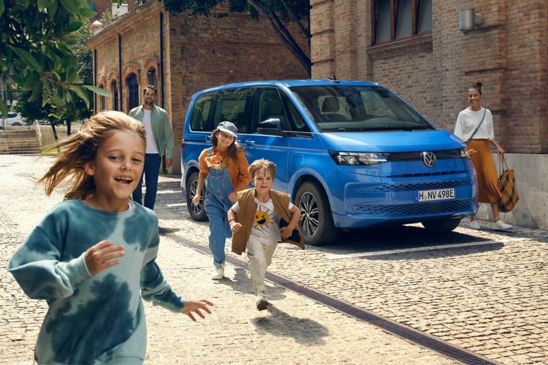 Une famille a garé le VW Multivan en ville au bord de la rue pour une excursion d’une journée.
