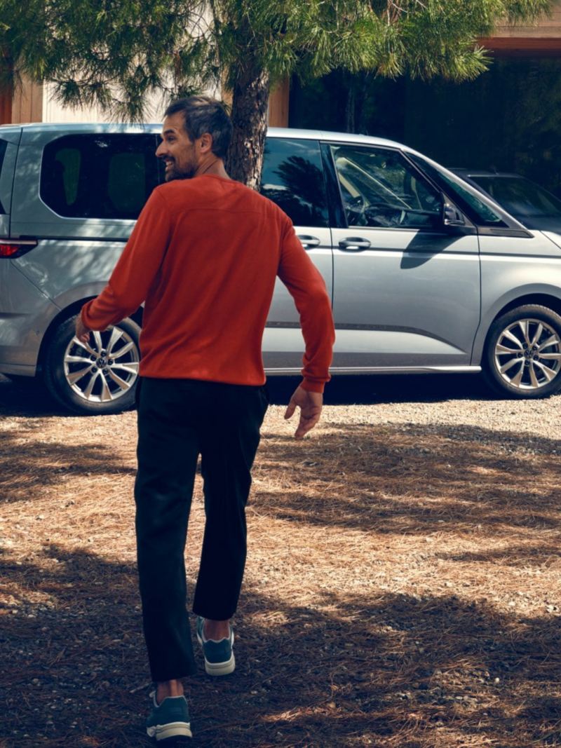 Δύο άνδρες περπατούν προς ένα σταθμευμένο VW Multivan Life.