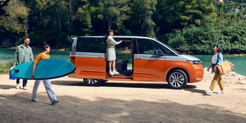 A family parks their VW Multivan Energetic on a river beach.