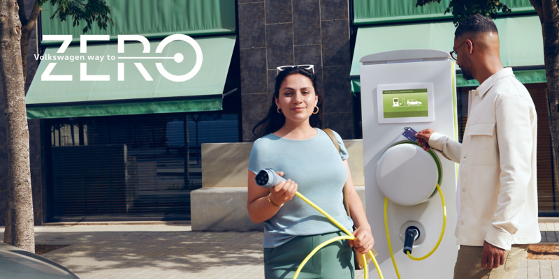 A woman and a man in front of a VW charging station.