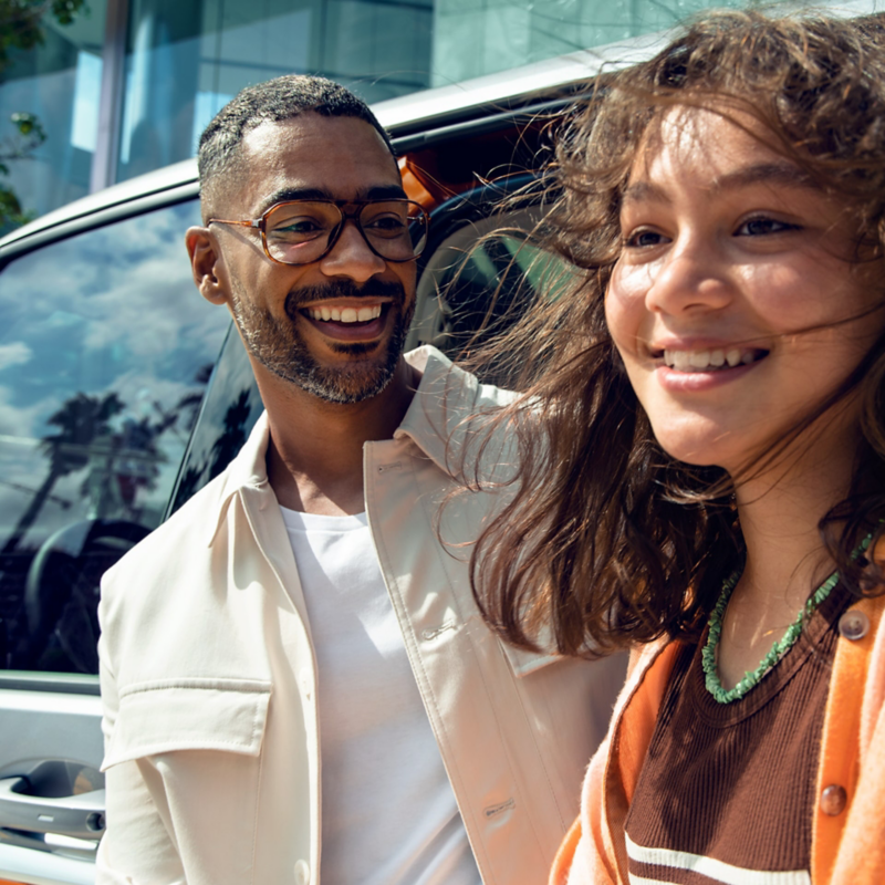 Two people smiling beside a Volkswagen vehicle with the door open