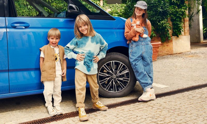 Tre bambini appoggiati a Volkswagen Multivan.