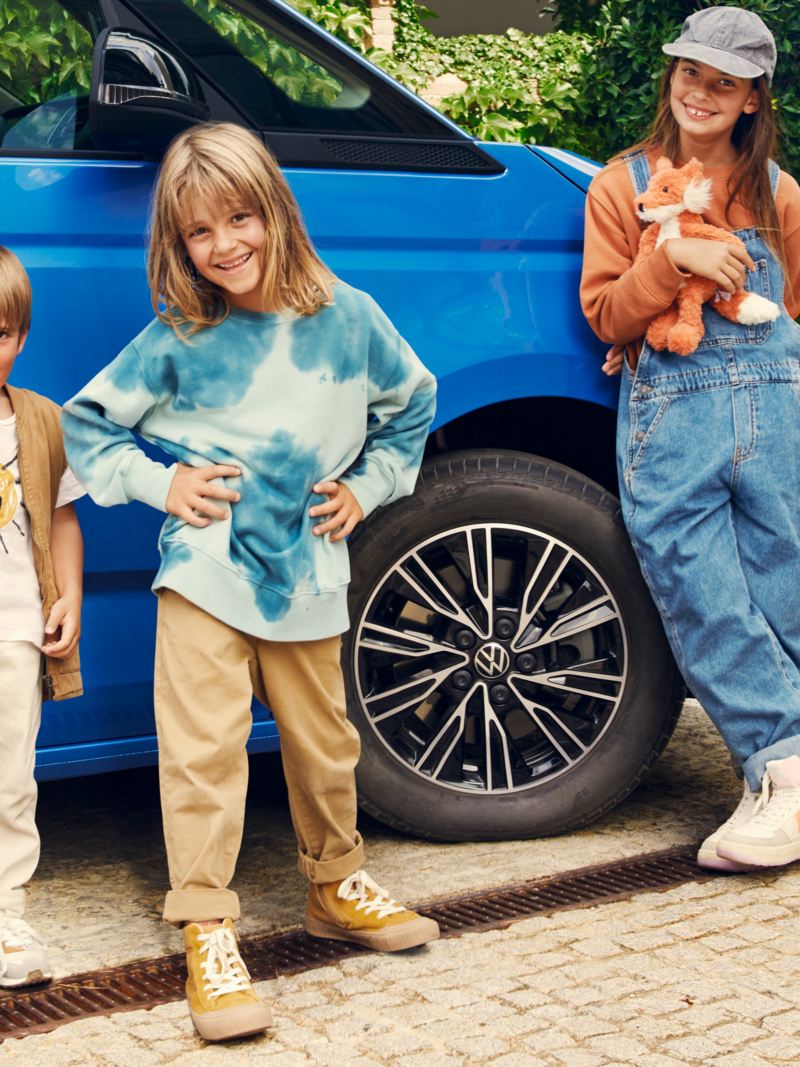 Tre bambini appoggiati a Volkswagen Multivan.