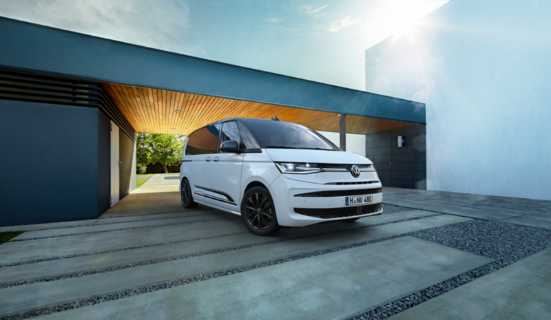 Dwaj mężczyźni przechodzą obok Volkswagena Multivana stojącego na podjeździe.