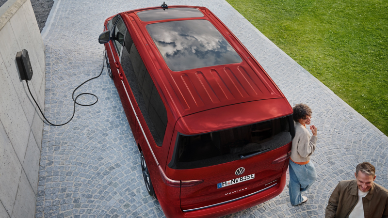 Ein VW Multivan steht auf einer Einfahrt, angeschlossen an eine Wallbox.