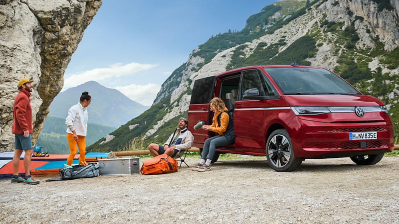 Vier Personen campen im VW Multivan vor Bergpanorama