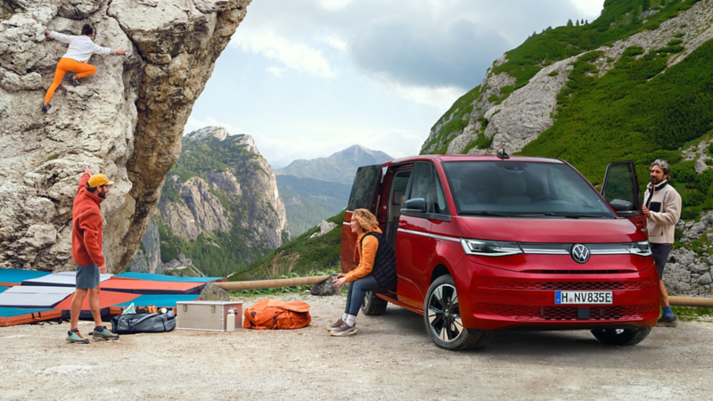 VW Multivan eHybrid parkt an einem Steilhang. Mehrere Klettersportler stehen beim Fahrzeug.