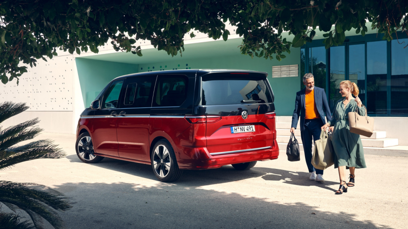 Ein Mann und eine Frau neben einem VW Multivan.