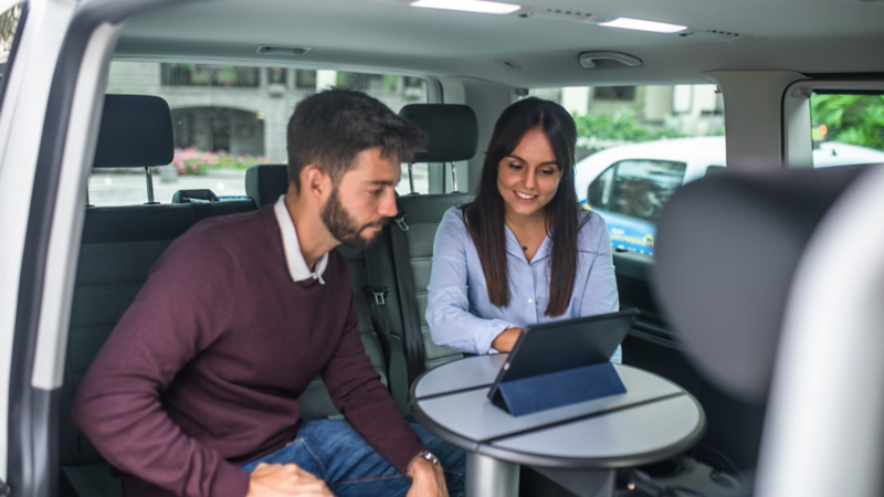 Geschäftsleute mit Tablet in einem VW Multivan