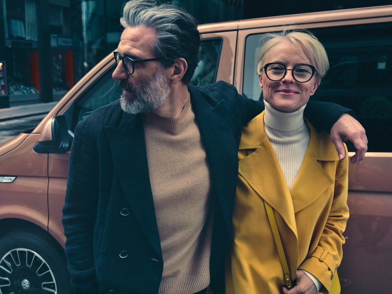 Een man en een vrouw staan ​​arm in arm voor een Volkswagen.