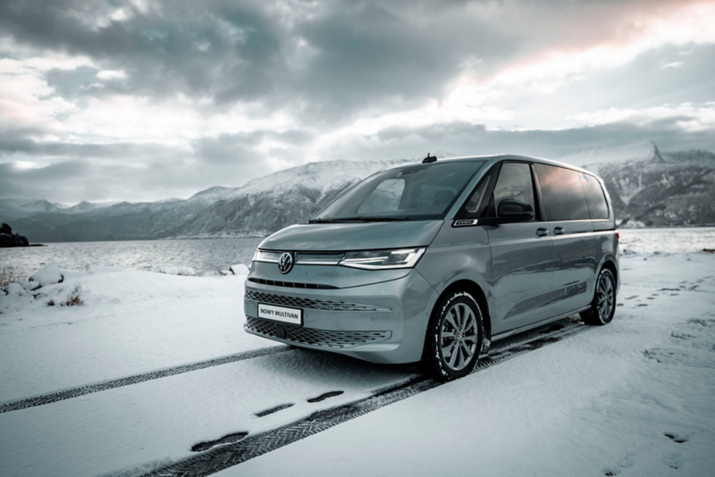 Volkswagen Multivan stoi na ośnieżonej drodze na tle gór.